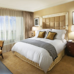 Bedroom,Elegant Beige Wall Paint Small Designer Bedroom With Beautiful Large White Bed Sheet Plus Stunning Large Headboard In Beige Color And Adorable Brown Wood Nighstand Tables On Combined Wonderful White Drum Table Lamps Also Soft White Transparent Curtains,The Best Modern Small Designer Bedrooms