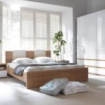 Bedroom,Impressive White Wall Paint Small Designer Bedroom With Stylish Natural Wood Bed Frame On Combined Nice White Bed Sheet And Cool White Brown Wood Nighstand Tables Plus Wonderful White Drum Table Lamps Also Gorgeous Potted Plants,The Best Modern Small Designer Bedrooms