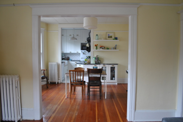 Apartments,Marvelous Light Yellow Wall Paint Apartment Kitchen Design Inspiration With Wonderful White Wood Kitchen Cabinet Plus Beautiful White Wood Floating Kitchen Cabinet And Gorgeous White Drum Pendant Lamp Also Cool Brown White Wood Dining Table Combined Trendy Brown Linen Wood Floor,Delightful Apartment Kitchen Designs And Style Modern