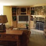 Interior,Exquisite Yellow Wall Paint Indoor Stone Fireplace Design With Rustic Corner Stone Fireplace And Wonderful Nature Bright Brown Entertainment Center Plus Beautiful Open Book Shelves Also Nice Brown Wood Narrow Table On Combined Unique Desk Lamp,Amazing Indoor Stone Fireplace Designs To A Living Room