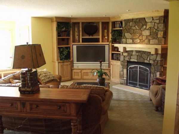 Interior,Exquisite Yellow Wall Paint Indoor Stone Fireplace Design With Rustic Corner Stone Fireplace And Wonderful Nature Bright Brown Entertainment Center Plus Beautiful Open Book Shelves Also Nice Brown Wood Narrow Table On Combined Unique Desk Lamp,Amazing Indoor Stone Fireplace Designs To A Living Room