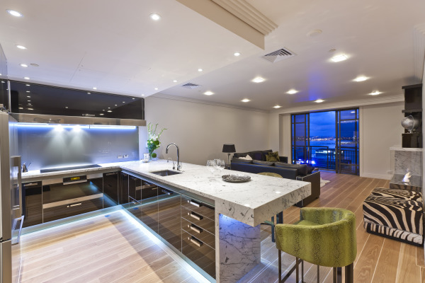 Apartments,Breathtaking Open Plan Apartment Kitchen Design Inspiration With Exquisite White Marble Countertop On Combined Modern Black Glossy Kitchen Cabinet Plus Beautiful Blue Led And Comfortable Black Leather Sofa Also Trendy Bright Brown Linen Wood Floor,Delightful Apartment Kitchen Designs And Style Modern